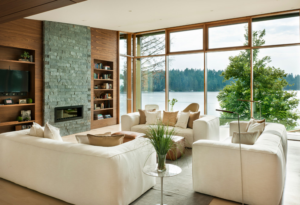 Ejemplo de sala de estar con biblioteca abierta actual con chimenea lineal, pared multimedia y alfombra