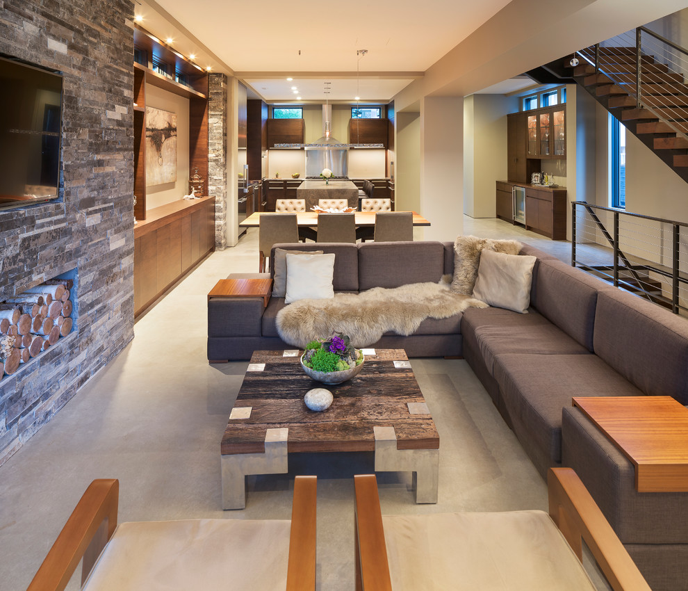 На фото: маленькая открытая гостиная комната в стиле модернизм с бежевыми стенами, бетонным полом, фасадом камина из камня и телевизором на стене без камина для на участке и в саду
