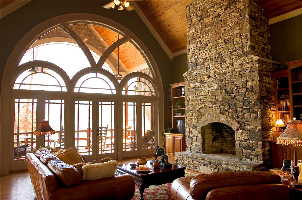 На фото: открытая гостиная комната в классическом стиле с коричневыми стенами, паркетным полом среднего тона, стандартным камином и фасадом камина из камня