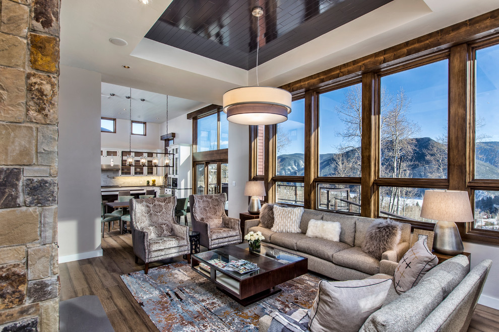 Inspiration for an expansive rustic open plan games room in Denver with beige walls, light hardwood flooring, a standard fireplace, a stone fireplace surround and brown floors.