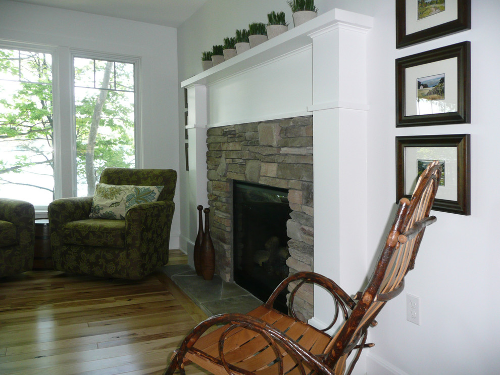 Cette photo montre une salle de séjour nature ouverte et de taille moyenne avec un mur blanc, parquet clair, une cheminée standard, un manteau de cheminée en pierre et un sol multicolore.