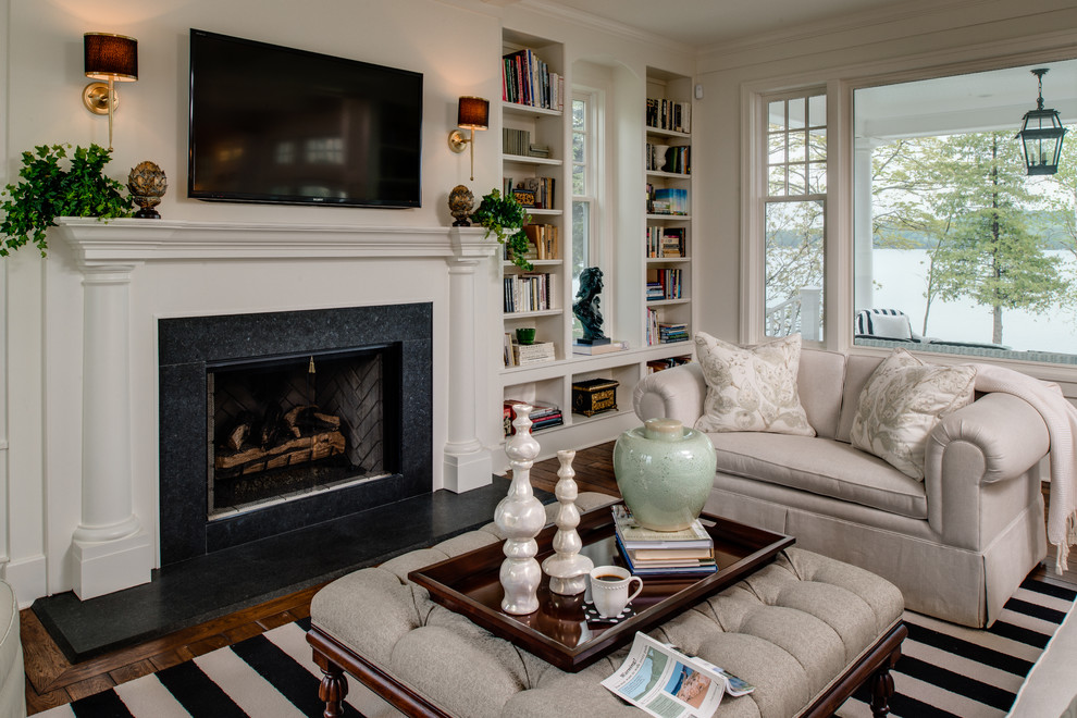 トラディショナルスタイルのおしゃれなファミリールーム (白い壁、濃色無垢フローリング、標準型暖炉、壁掛け型テレビ、茶色い床) の写真