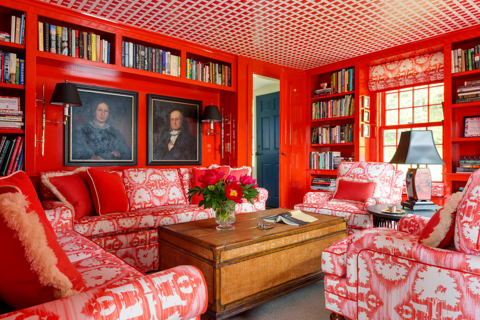 Cette image montre une petite salle de séjour bohème fermée avec une bibliothèque ou un coin lecture et un mur rouge.
