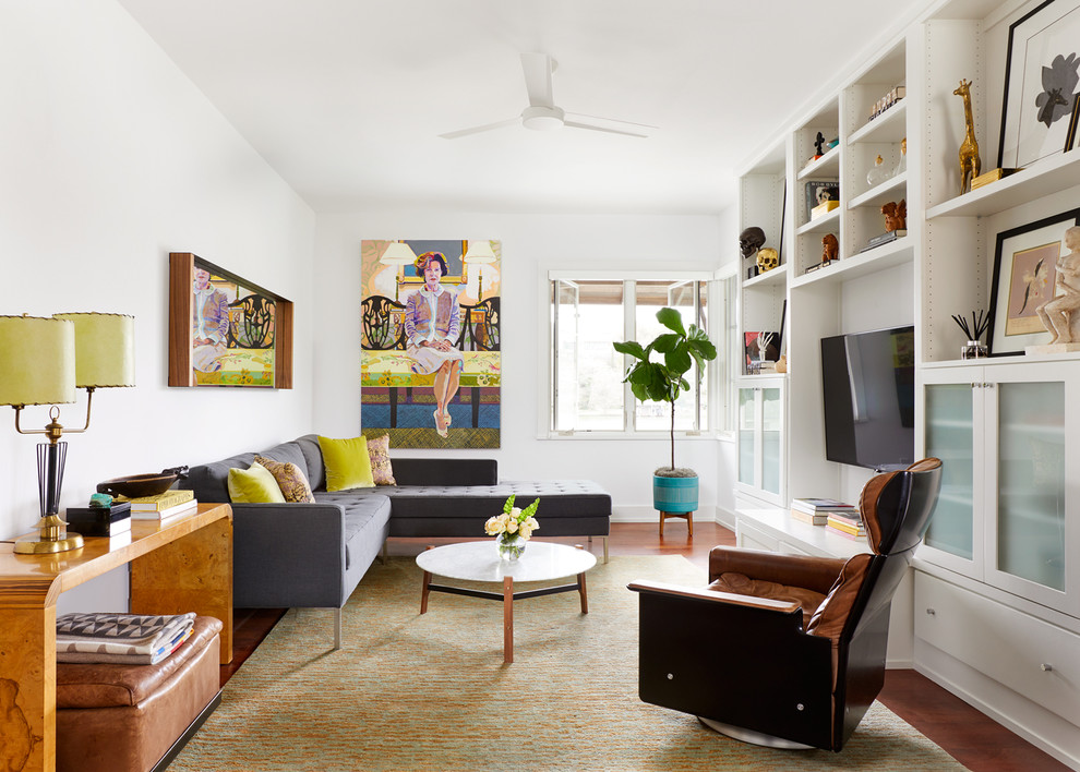 Family room library - large eclectic enclosed medium tone wood floor and brown floor family room library idea in Austin with white walls, no fireplace and a media wall