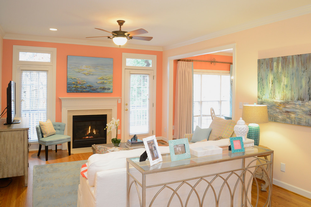 Источник вдохновения для домашнего уюта: изолированная гостиная комната среднего размера в стиле фьюжн с оранжевыми стенами, светлым паркетным полом, стандартным камином, отдельно стоящим телевизором и фасадом камина из камня