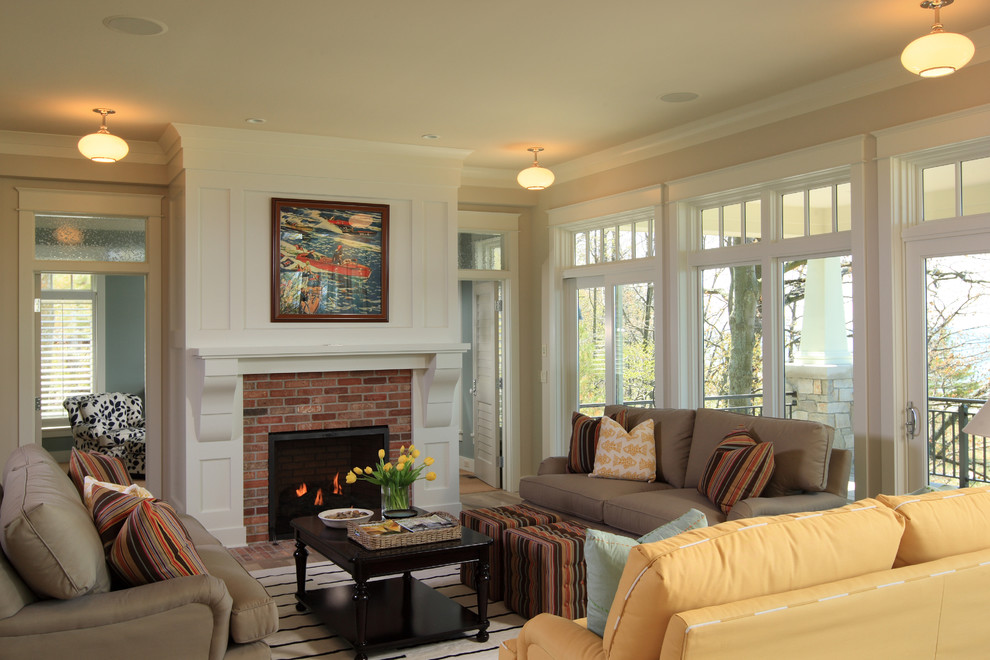 Imagen de sala de estar abierta marinera con paredes beige, suelo de madera clara, todas las chimeneas, marco de chimenea de ladrillo y televisor colgado en la pared