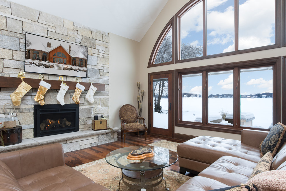 Example of a large transitional enclosed dark wood floor family room design in Minneapolis with beige walls, a standard fireplace, a stone fireplace and a wall-mounted tv