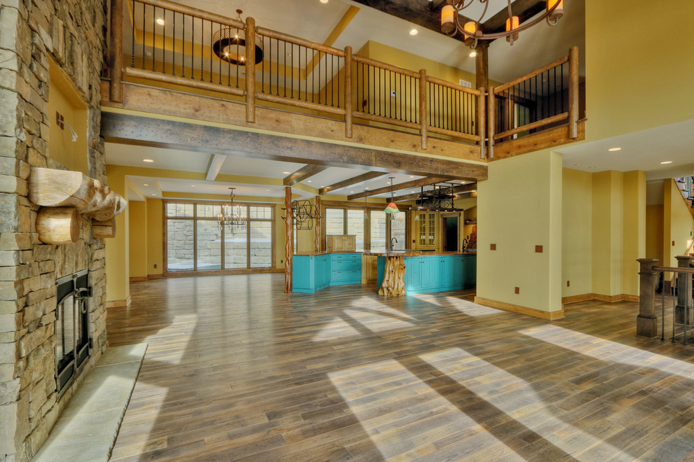 Immagine di un ampio soggiorno stile americano stile loft con sala della musica, pareti gialle, pavimento in legno massello medio, camino classico, cornice del camino in pietra e parete attrezzata