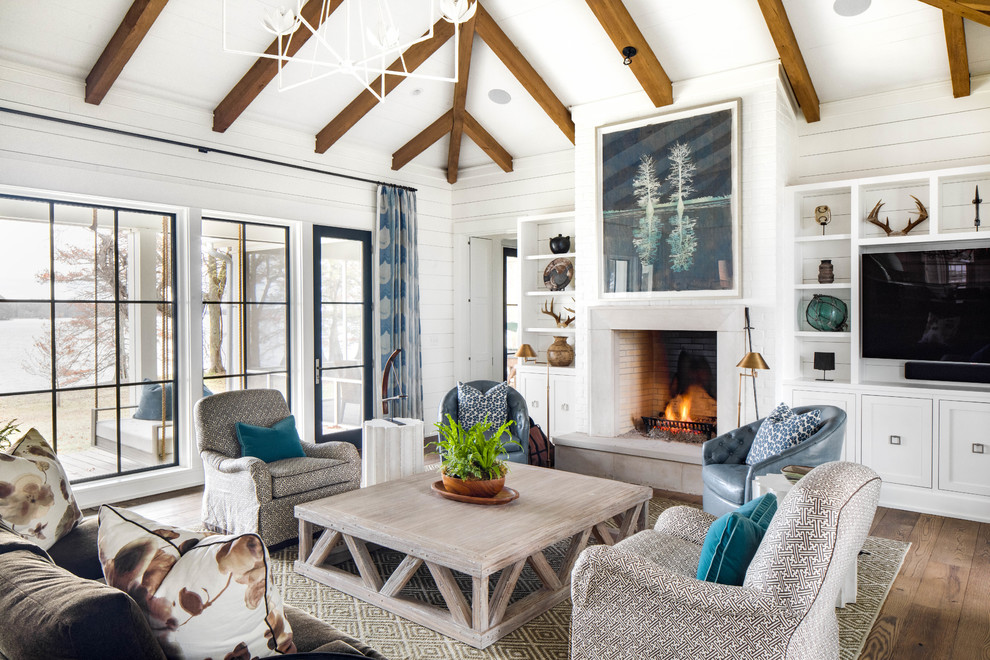 Imagen de sala de estar campestre con paredes blancas, suelo de madera oscura, todas las chimeneas, pared multimedia y alfombra