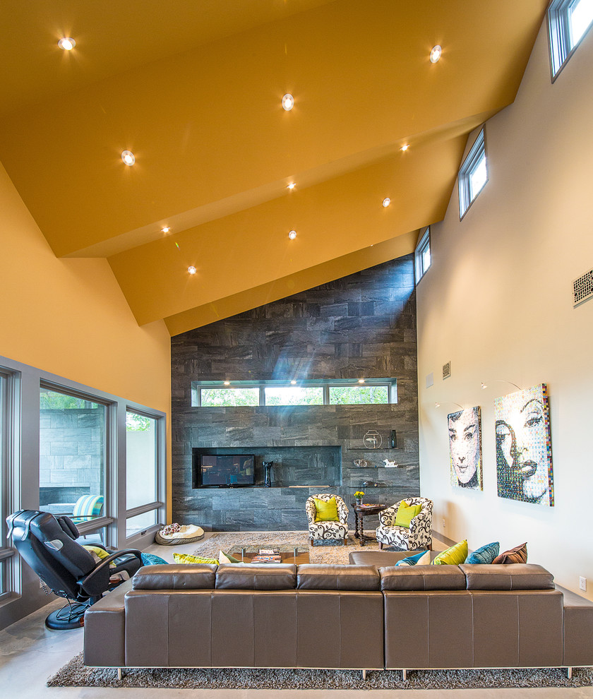 Mittelgroßes, Offenes Modernes Wohnzimmer mit Gaskamin, Kaminumrandung aus Stein, gelber Wandfarbe, Betonboden und freistehendem TV in Austin