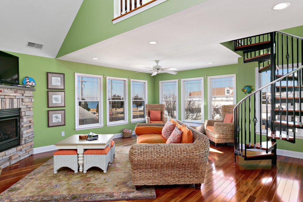 Inspiration for a large coastal open concept medium tone wood floor and brown floor family room remodel in Philadelphia with green walls, a stone fireplace and a wall-mounted tv