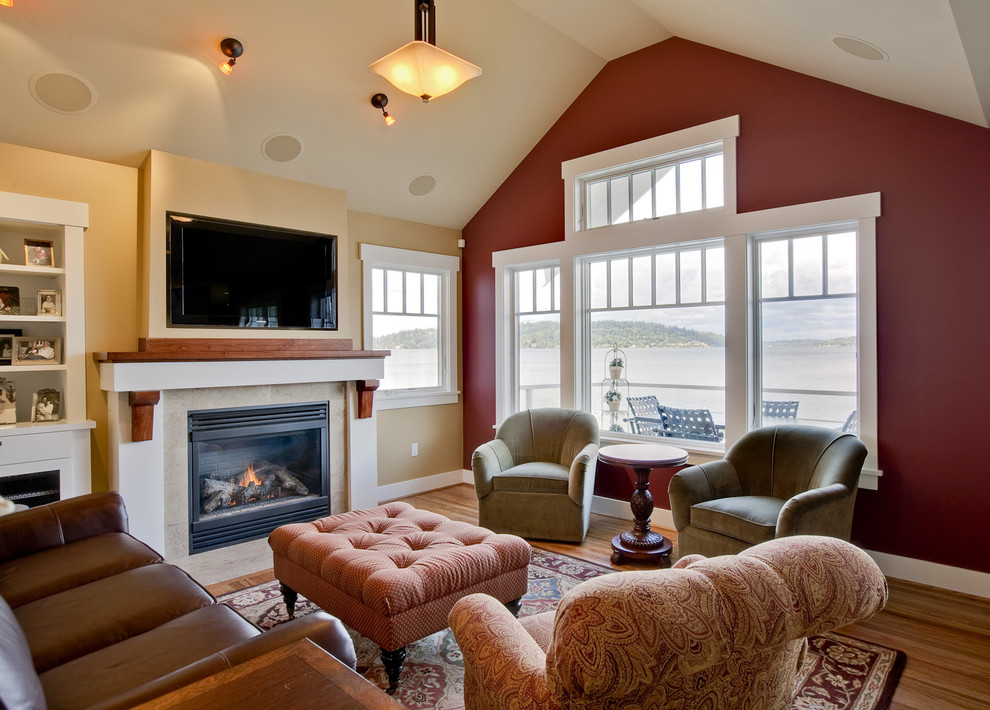 Idée de décoration pour une salle de séjour tradition avec un mur rouge, un sol en bois brun, une cheminée standard et un téléviseur fixé au mur.