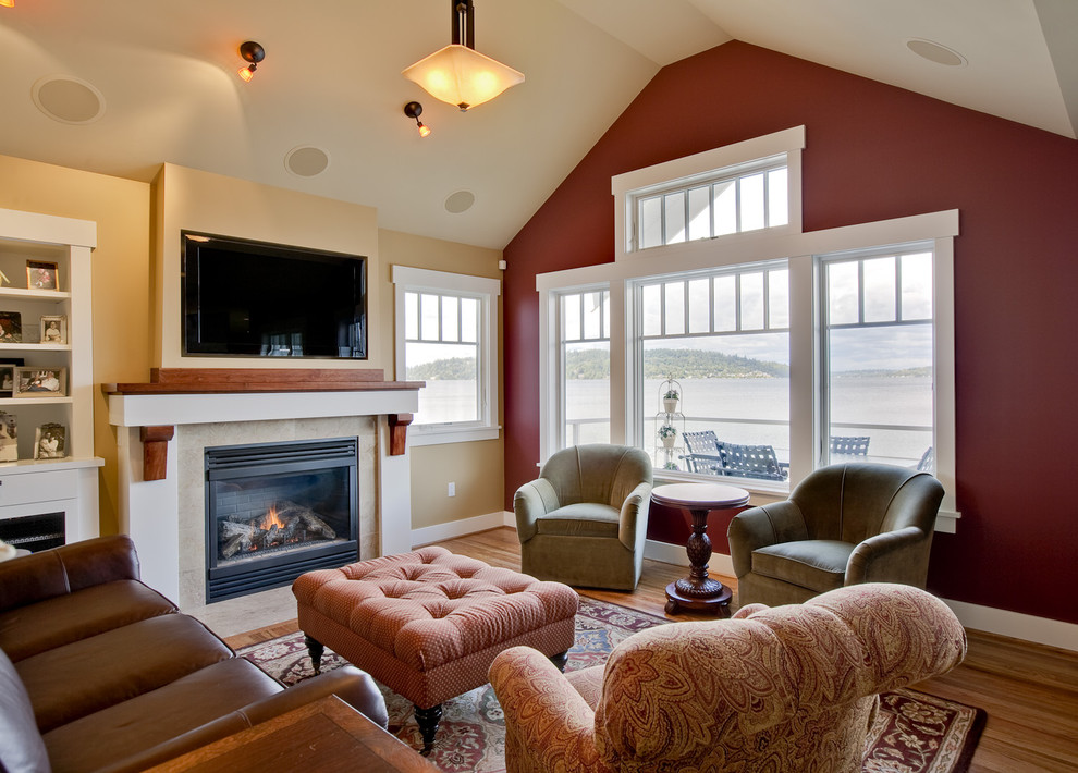 Elegant medium tone wood floor family room photo in Seattle with red walls, a standard fireplace and a wall-mounted tv