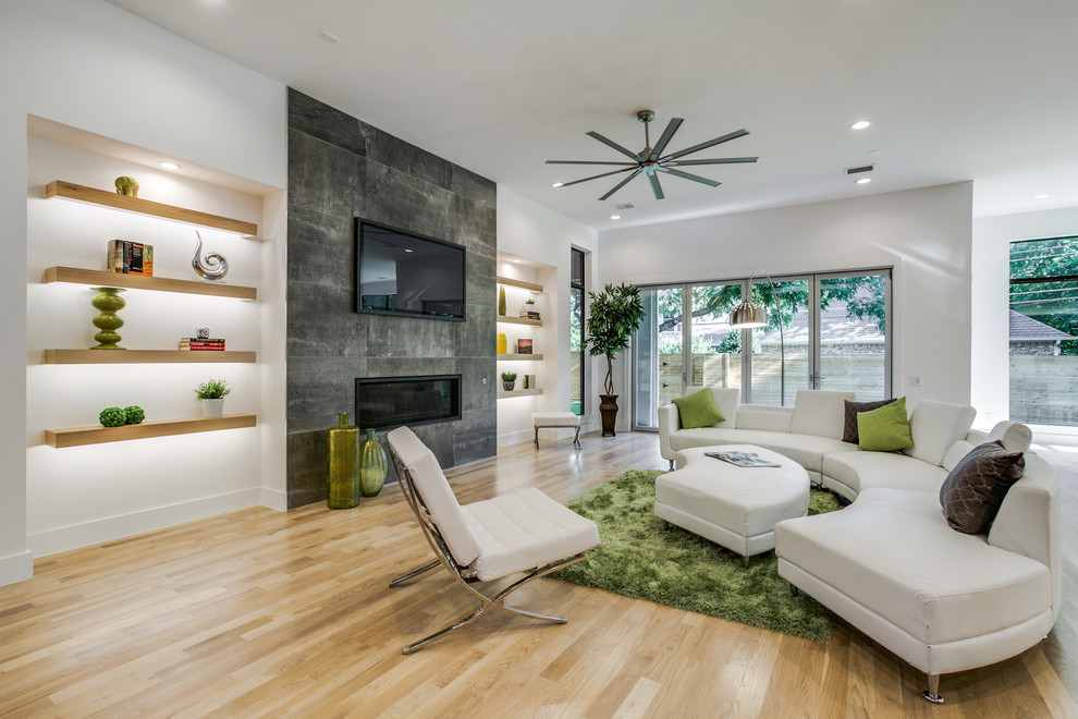 Diseño de sala de estar abierta actual con paredes blancas, suelo de madera clara, chimenea lineal y televisor colgado en la pared