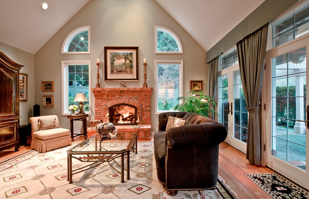 Example of a classic light wood floor family room design in Seattle with a standard fireplace, a brick fireplace and a concealed tv