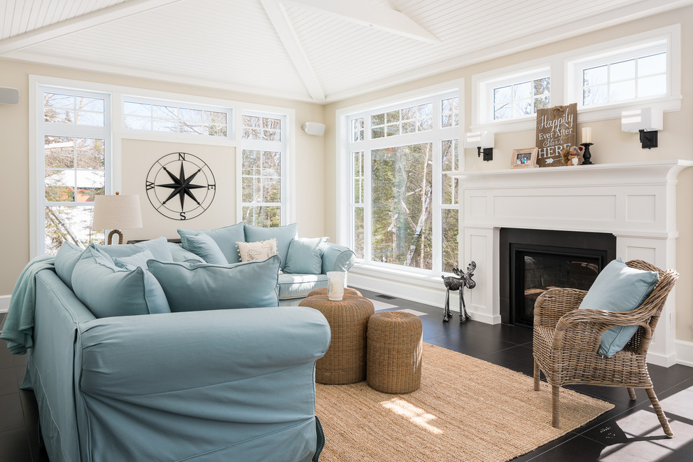 Идея дизайна: гостиная комната в морском стиле с бежевыми стенами, стандартным камином, черным полом и синим диваном