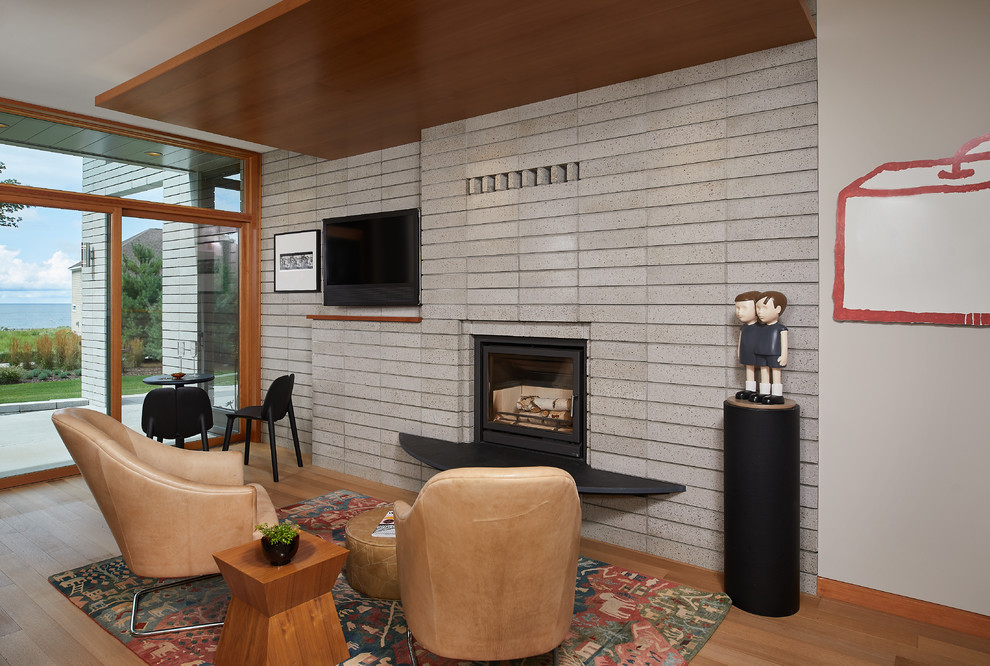 Cette image montre une salle de séjour vintage ouverte avec un mur blanc, un sol en bois brun, un poêle à bois, un téléviseur fixé au mur, un manteau de cheminée en brique, un sol marron et un mur en parement de brique.