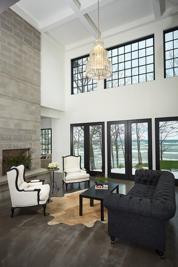 Modern open plan games room with white walls, dark hardwood flooring, a standard fireplace, a concrete fireplace surround, brown floors and a coffered ceiling.