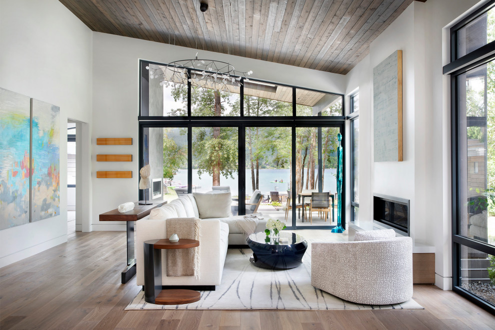 Großes, Offenes Modernes Wohnzimmer mit weißer Wandfarbe, braunem Holzboden, Gaskamin, verputzter Kaminumrandung und braunem Boden in Sonstige