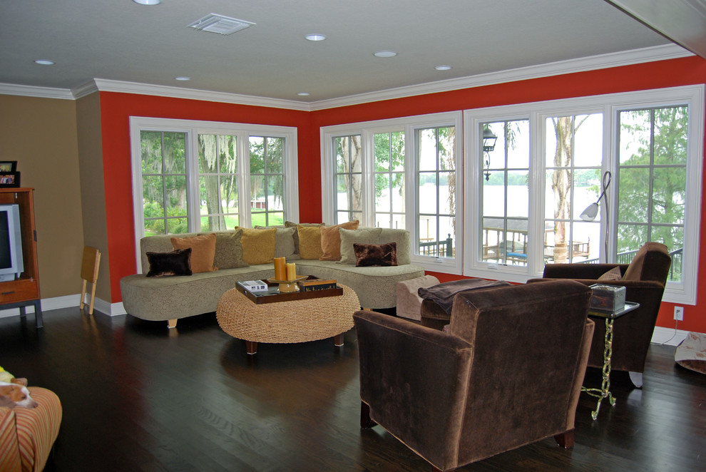 Inspiration pour une grande salle de séjour craftsman ouverte avec un mur rouge, parquet foncé, aucune cheminée, un téléviseur encastré et un sol marron.