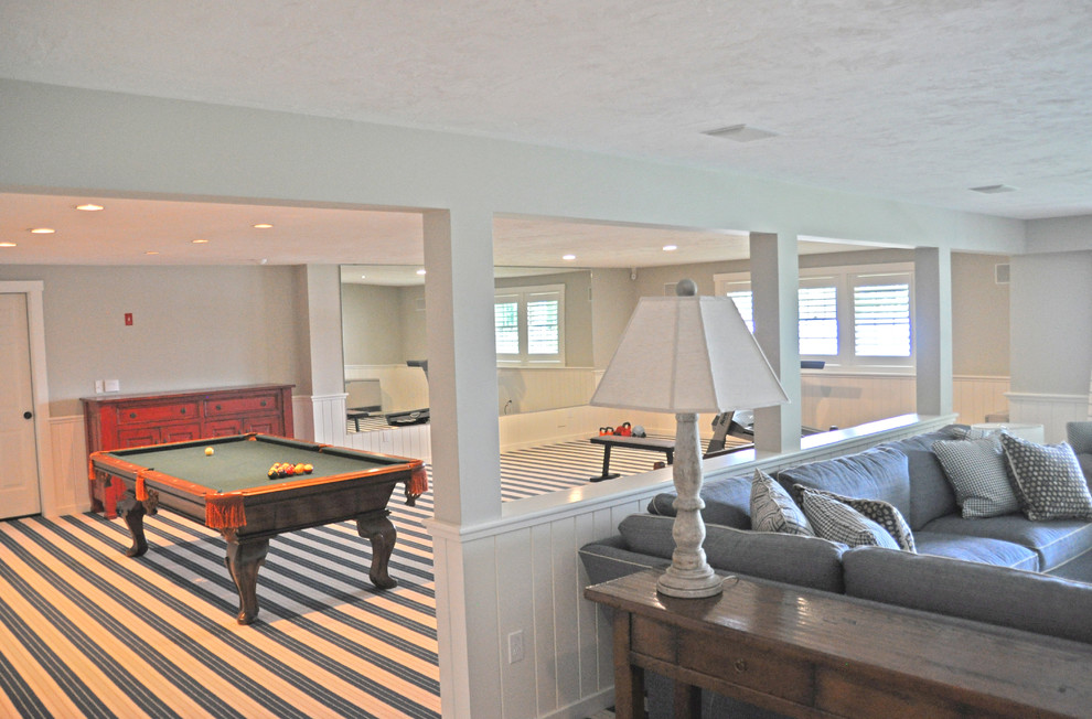 This is an example of a large classic open plan games room in Portland Maine with a game room, grey walls, carpet, a standard fireplace, a stone fireplace surround, a wall mounted tv and blue floors.