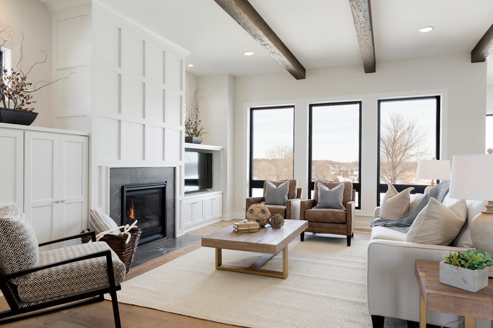 Landhaus Wohnzimmer mit weißer Wandfarbe, braunem Holzboden, Kamin, gefliester Kaminumrandung, TV-Wand und braunem Boden in Minneapolis