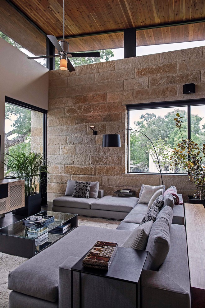 Imagen de sala de estar abierta contemporánea grande sin chimenea con paredes beige, suelo de madera oscura y televisor colgado en la pared