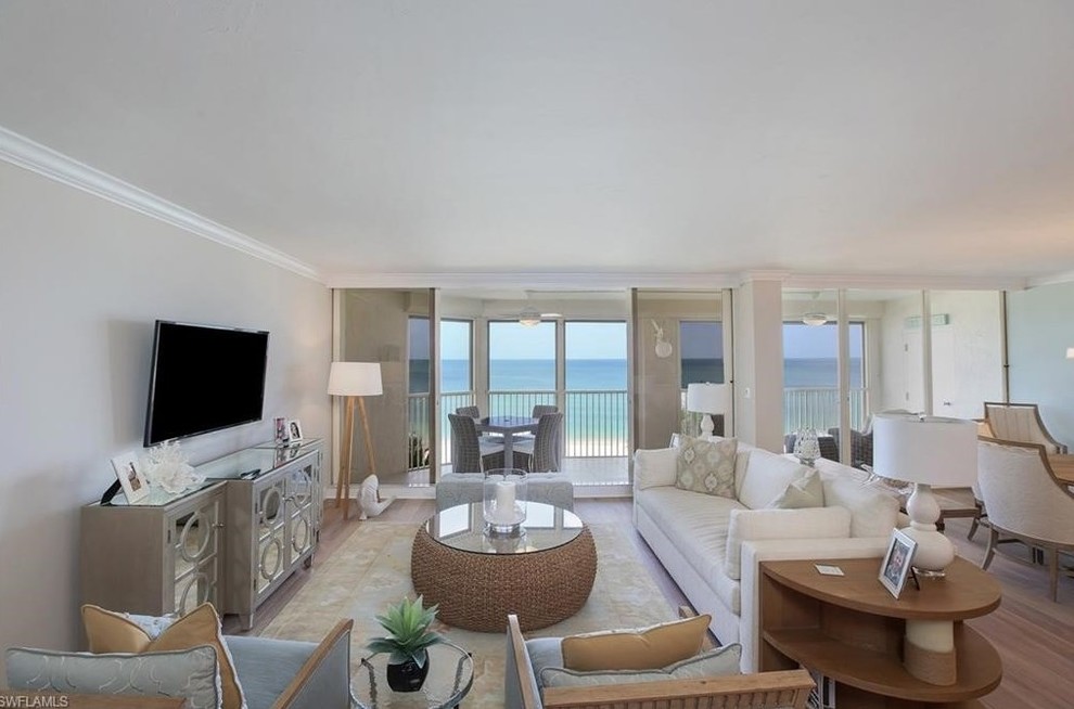 Immagine di un soggiorno stile marinaro di medie dimensioni e aperto con pareti beige, parquet chiaro e TV a parete