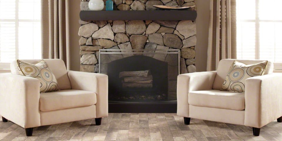 他の地域にあるトラディショナルスタイルのおしゃれなファミリールーム (ベージュの壁、ラミネートの床、標準型暖炉、石材の暖炉まわり、ベージュの床) の写真