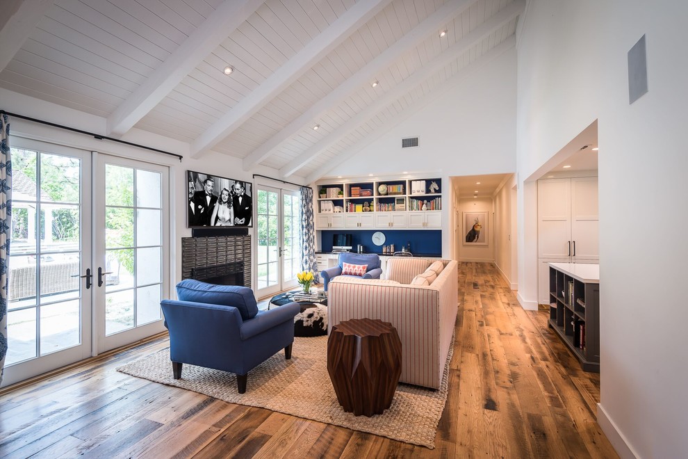 Cette photo montre une salle de séjour nature de taille moyenne et ouverte avec une cheminée standard, un manteau de cheminée en métal, un téléviseur fixé au mur, un mur blanc et un sol en bois brun.