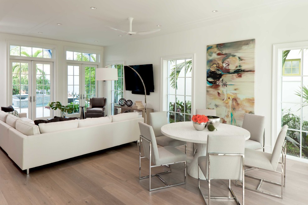 На фото: большая открытая гостиная комната в стиле неоклассика (современная классика) с белыми стенами, паркетным полом среднего тона и телевизором на стене