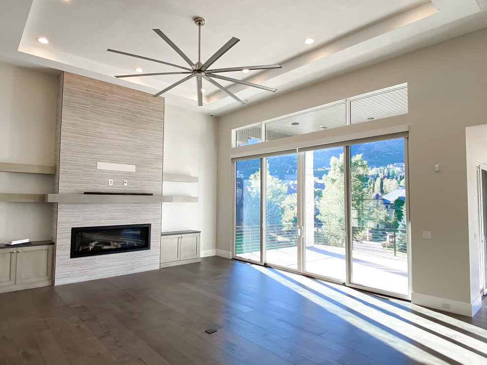 Inspiration for a large contemporary open concept dark wood floor, brown floor and coffered ceiling family room remodel in Salt Lake City with white walls, a standard fireplace, a tile fireplace and no tv