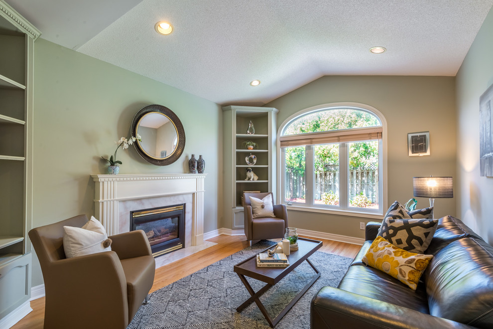 Exemple d'une petite salle de séjour tendance avec un mur vert, parquet clair, une cheminée standard, un manteau de cheminée en bois et un sol jaune.