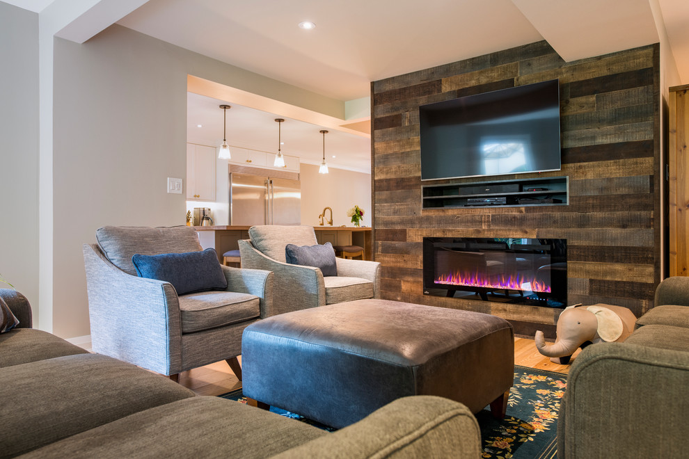 Mid-sized trendy open concept light wood floor and beige floor family room photo with gray walls, a standard fireplace, a wood fireplace surround and a wall-mounted tv