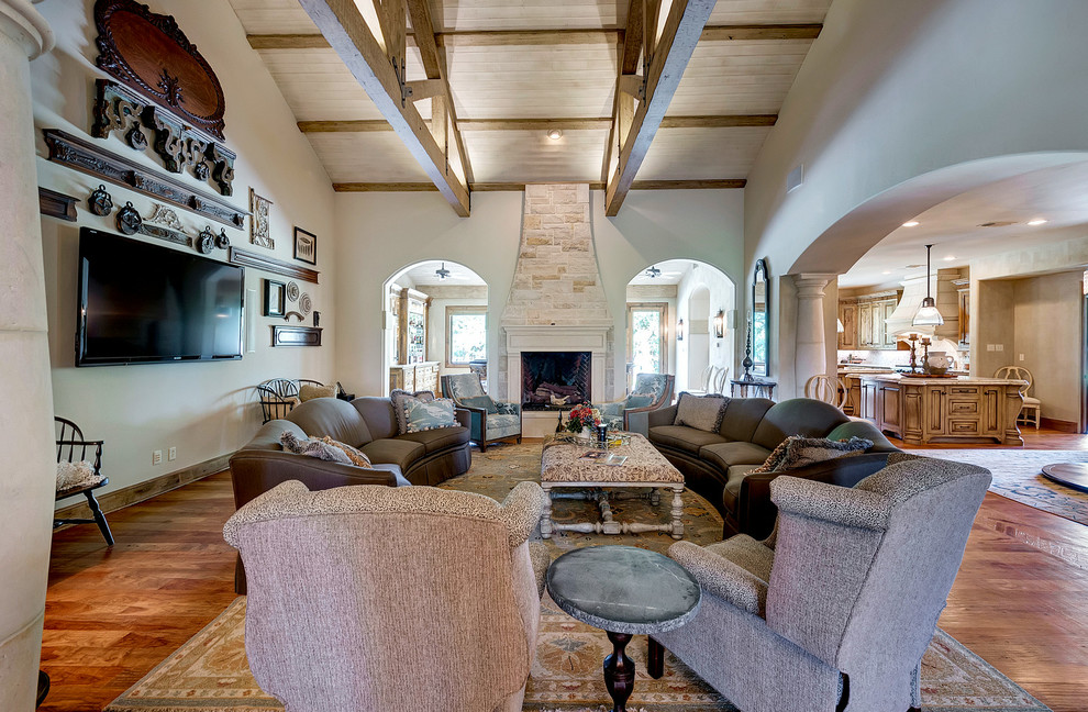 Mid-sized tuscan enclosed dark wood floor and brown floor family room photo in Dallas with white walls, a standard fireplace, a stone fireplace and a wall-mounted tv
