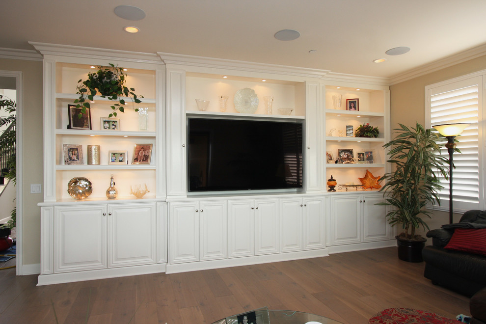 Imagen de sala de estar cerrada tradicional renovada grande con paredes beige, suelo de madera en tonos medios y pared multimedia