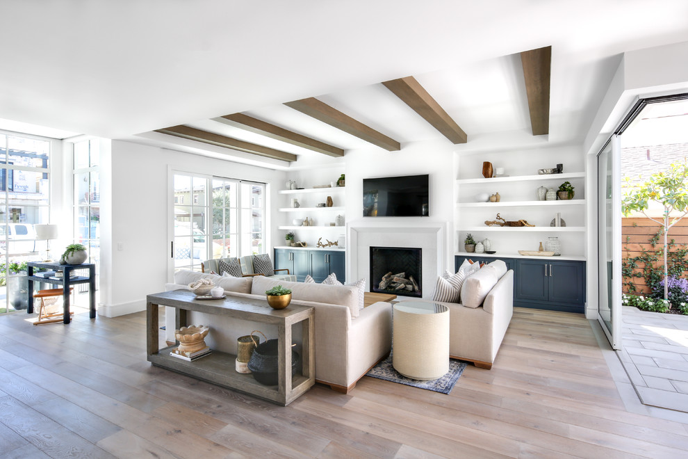 Offenes Maritimes Wohnzimmer mit weißer Wandfarbe, braunem Holzboden, Kamin, TV-Wand und braunem Boden in Orange County