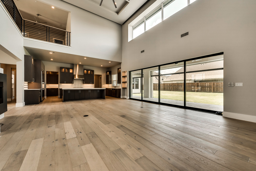 This is an example of an expansive classic open plan games room in Dallas with grey walls, medium hardwood flooring, a two-sided fireplace, a metal fireplace surround, a wall mounted tv and beige floors.