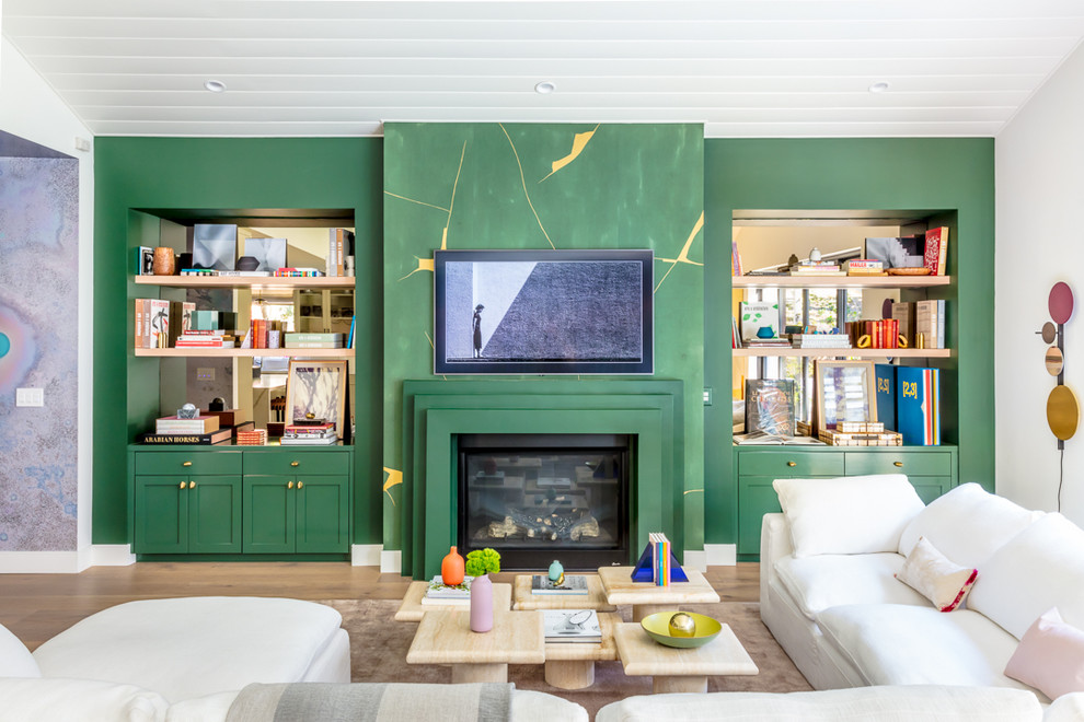 Imagen de salón vintage con paredes verdes, suelo de madera clara y todas las chimeneas