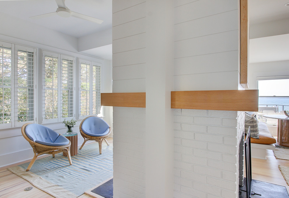 Inspiration pour une grande salle de séjour marine ouverte avec un mur blanc, parquet clair, une cheminée double-face, un manteau de cheminée en lambris de bois et un téléviseur fixé au mur.