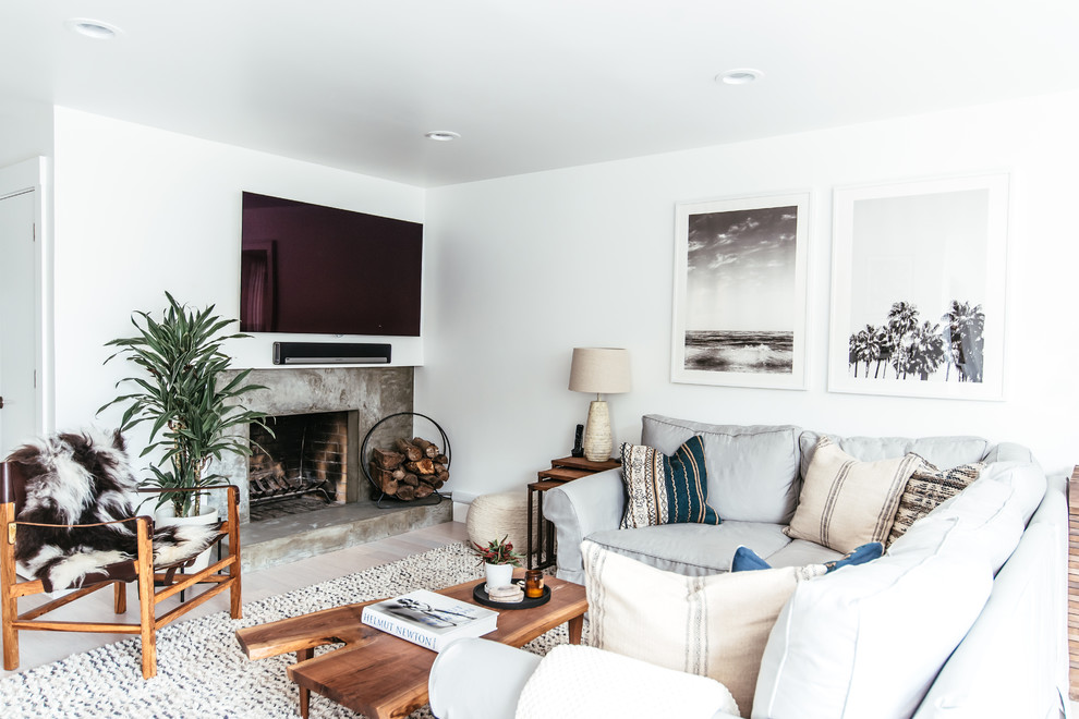 Modelo de sala de estar nórdica con paredes blancas, suelo de madera clara, todas las chimeneas, marco de chimenea de hormigón, televisor colgado en la pared y suelo beige