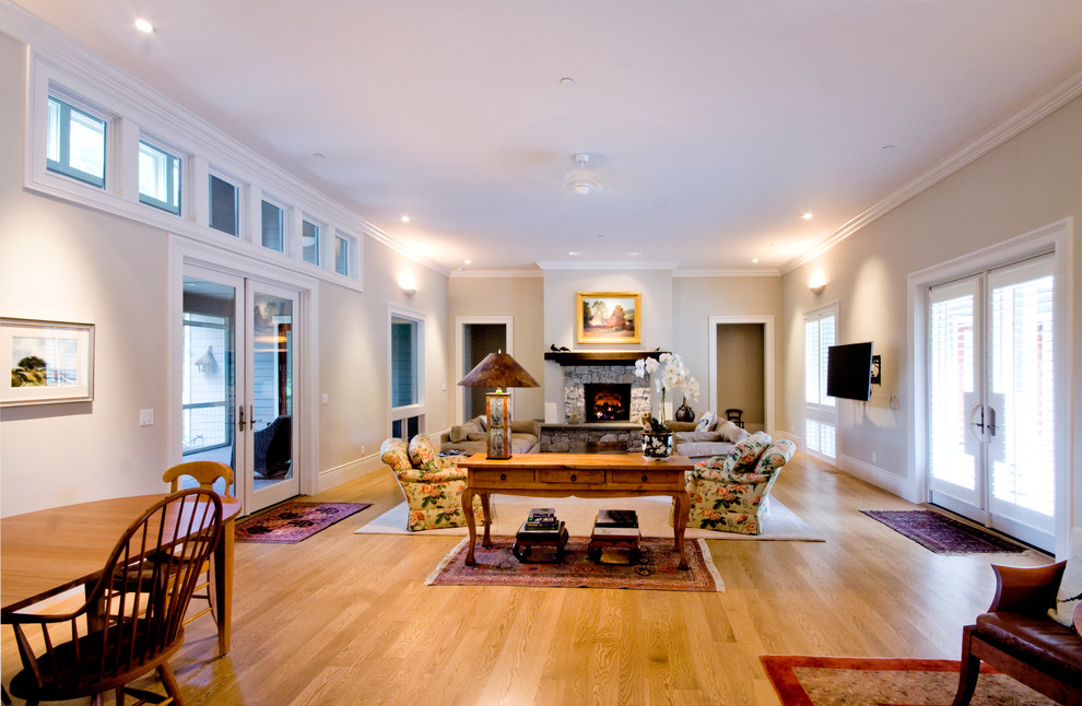 Foto de sala de estar abierta de estilo de casa de campo de tamaño medio con paredes beige, suelo de madera clara, todas las chimeneas y marco de chimenea de piedra