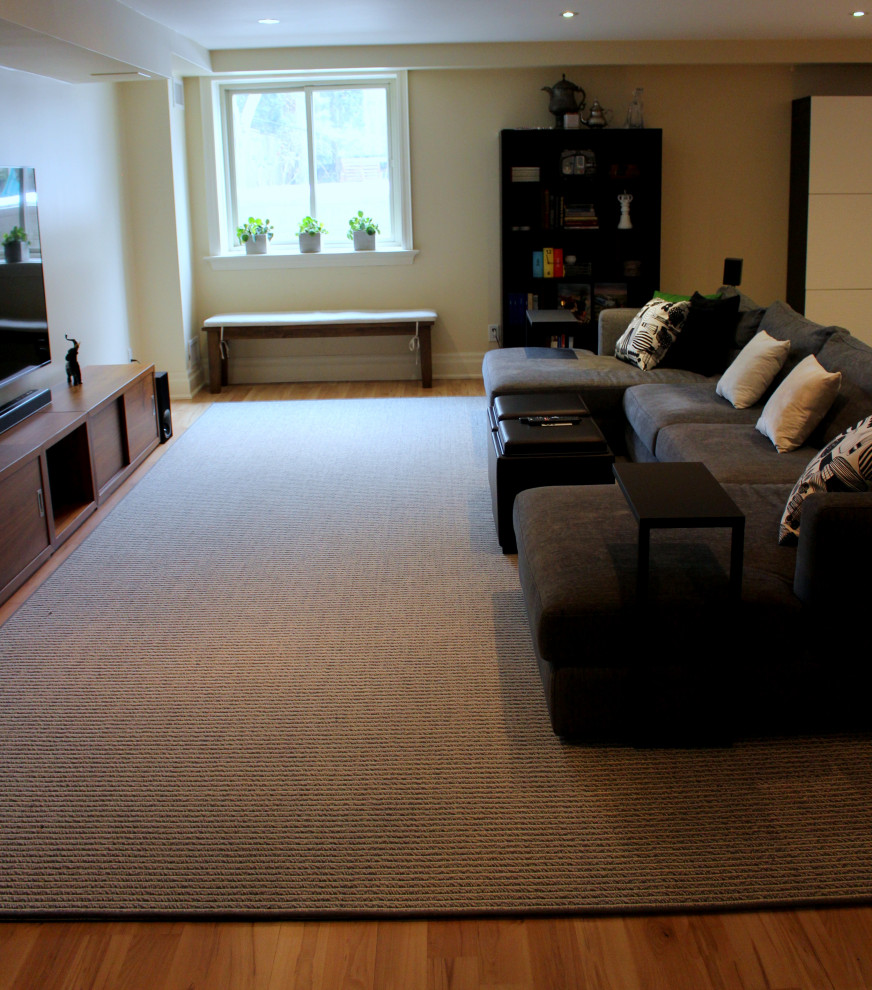 Modelo de sala de estar cerrada actual grande sin chimenea con paredes beige, suelo laminado, televisor colgado en la pared y suelo beige