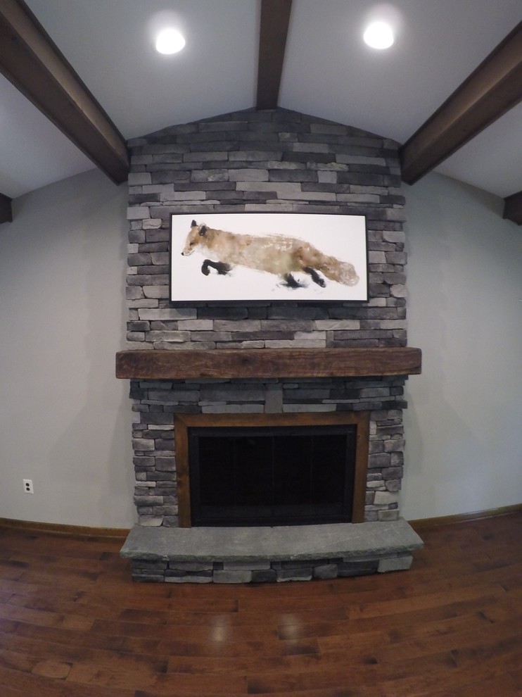 Inspiration for a medium sized rustic games room in Philadelphia with a standard fireplace, a stone fireplace surround, a wall mounted tv and medium hardwood flooring.