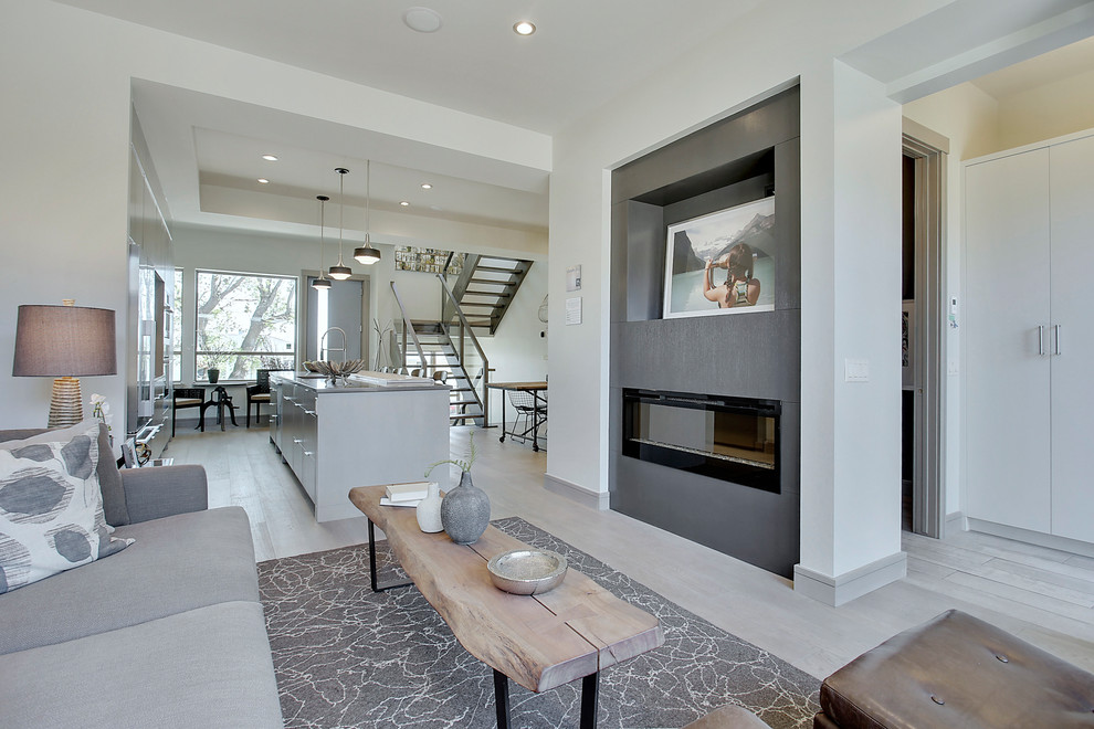 Exemple d'une salle de séjour tendance ouverte et de taille moyenne avec un mur gris, un sol en bois brun, une cheminée standard, un manteau de cheminée en bois, un téléviseur encastré et un sol gris.