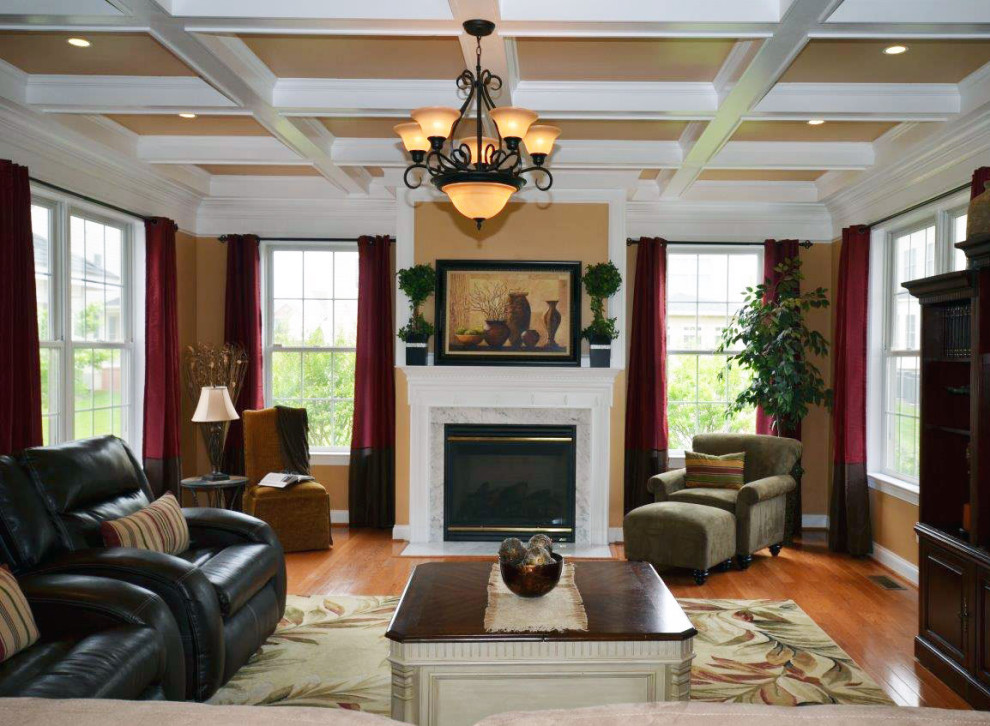 Klassisches Wohnzimmer mit gelber Wandfarbe, braunem Holzboden, Kamin, Kaminumrandung aus Holz, freistehendem TV, braunem Boden und Kassettendecke