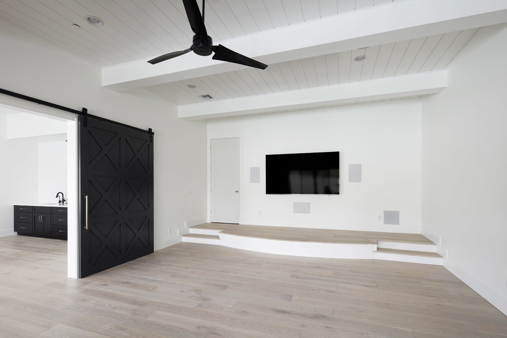Пример оригинального дизайна: большая двухуровневая комната для игр в стиле кантри с белыми стенами, светлым паркетным полом, стандартным камином, фасадом камина из кирпича, телевизором на стене и бежевым полом