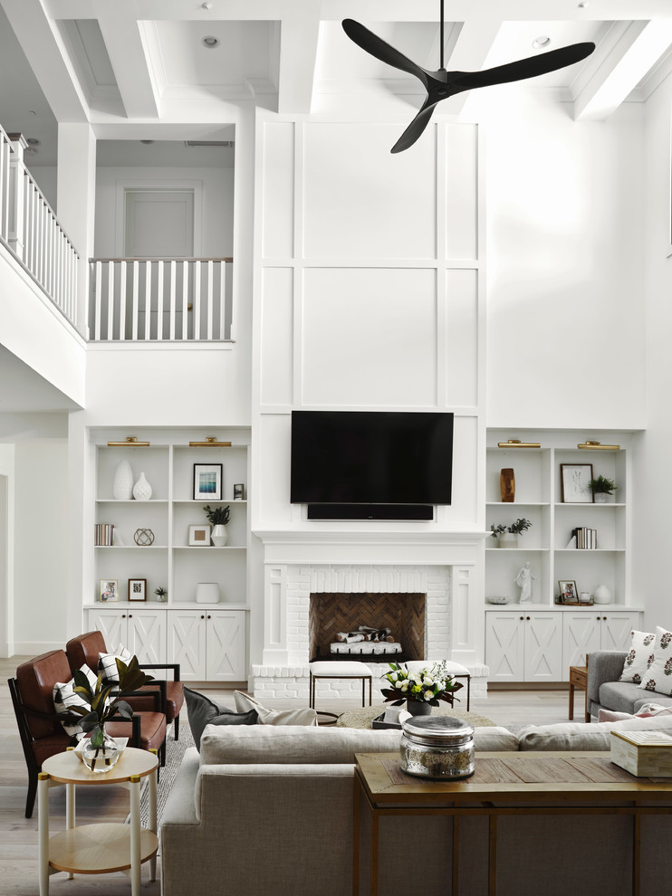Bild på ett stort lantligt allrum på loftet, med ett spelrum, vita väggar, ljust trägolv, en standard öppen spis, en spiselkrans i tegelsten, en väggmonterad TV och beiget golv