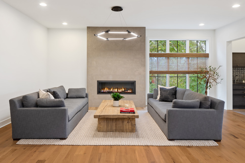 Inspiration for a medium sized modern open plan games room in Cincinnati with white walls, light hardwood flooring, a standard fireplace and beige floors.