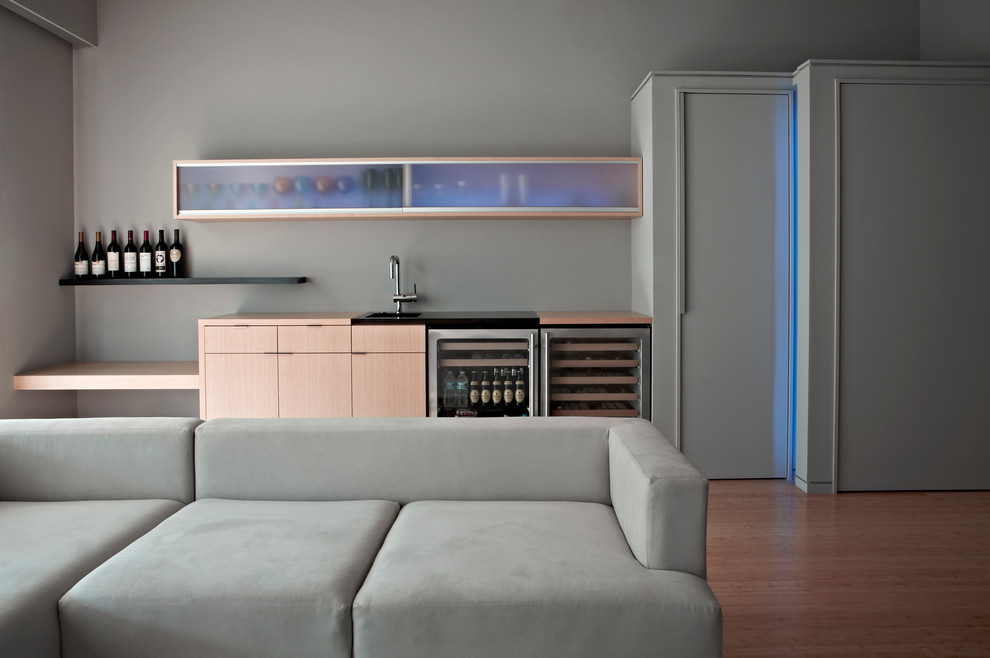 Diseño de sala de estar con barra de bar contemporánea sin chimenea y televisor con paredes grises y suelo de madera en tonos medios